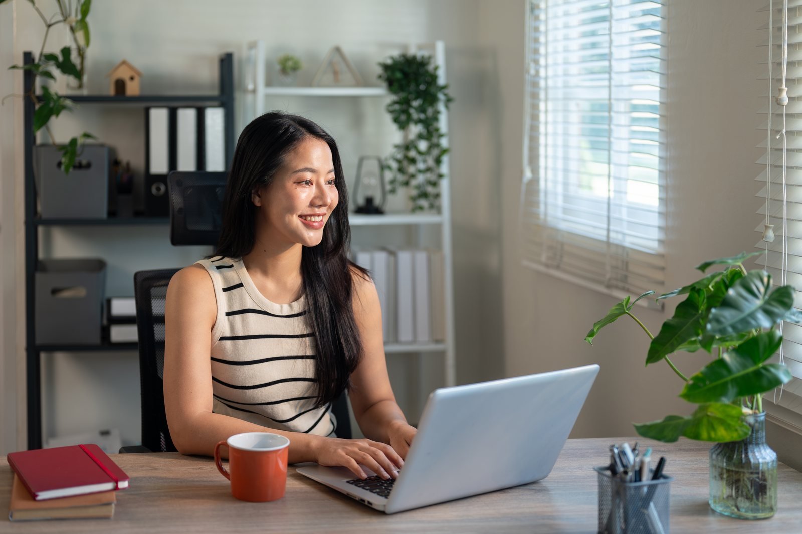 Professional smiling while working at a laptop in a bright home office
