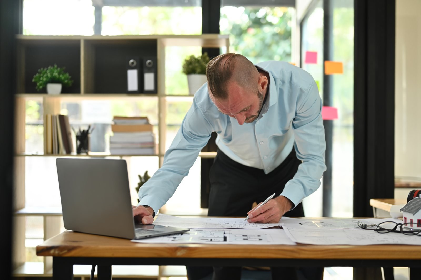 Construction professional reviewing plans beside a laptop