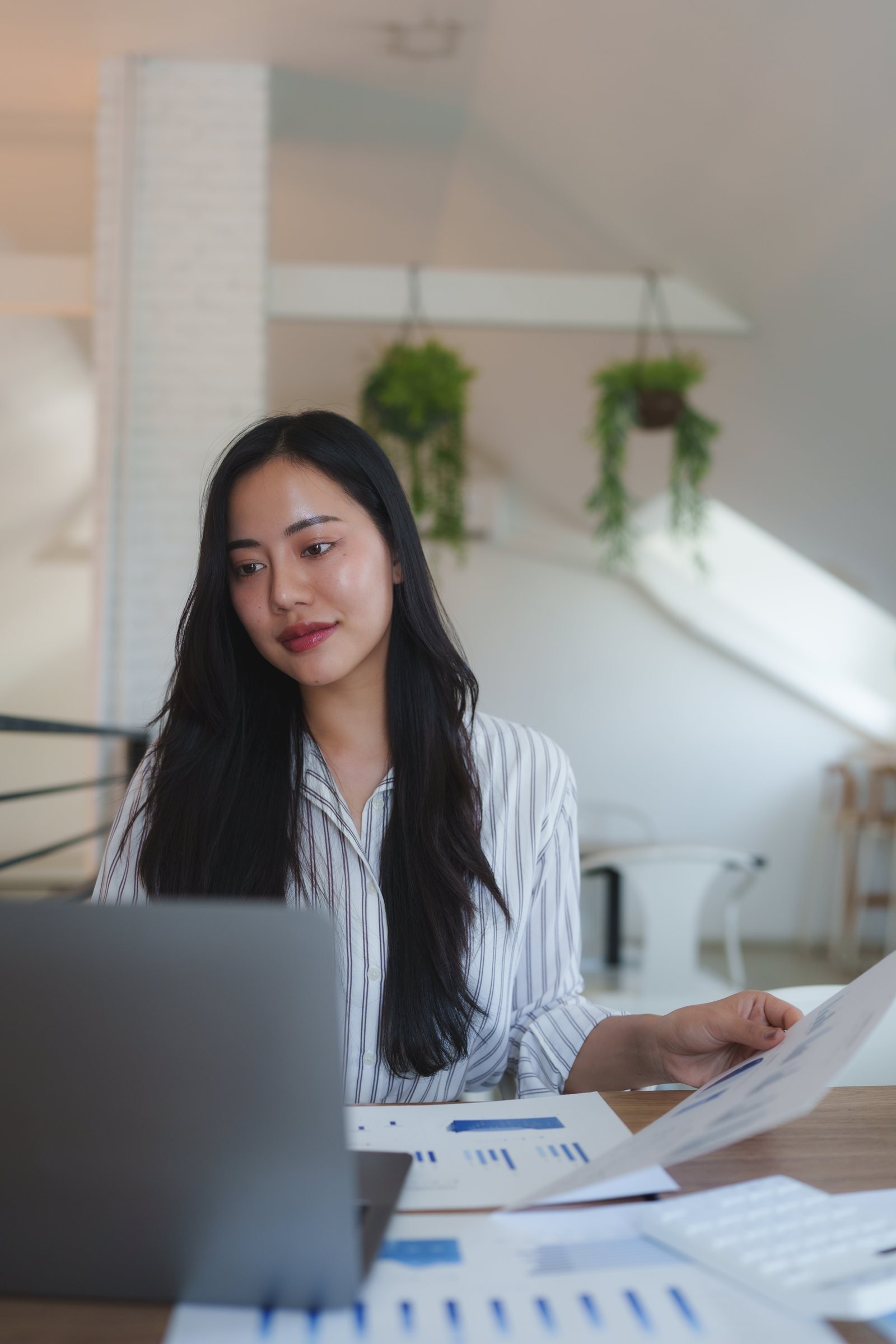 Finance professional reviewing reports beside a laptop