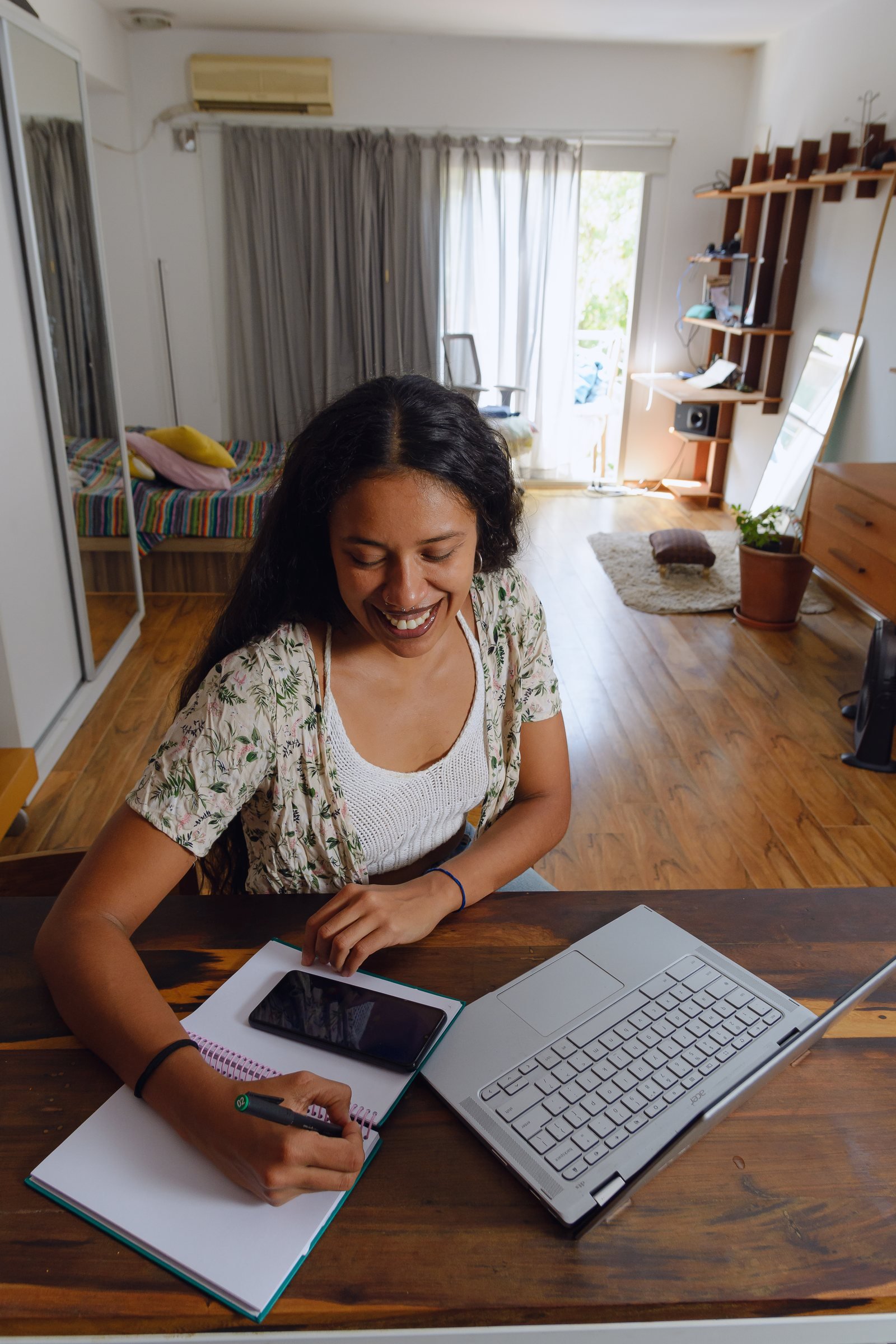 Remote professional writing notes beside a laptop at a home desk